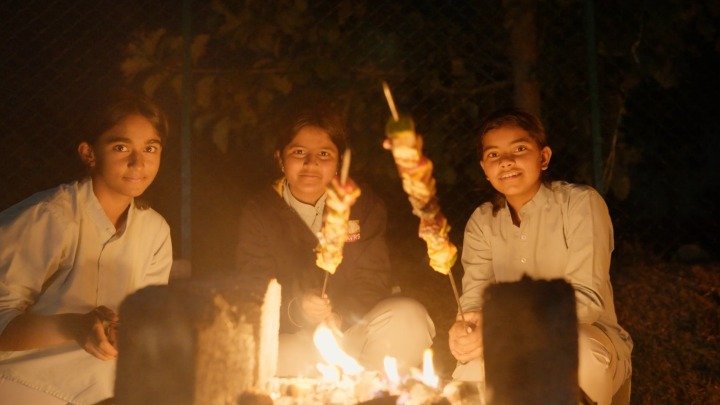 Students roasting food around a campfire at night
